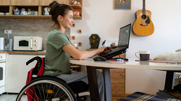 woman sitting in wheelchair smiling looking at laptop